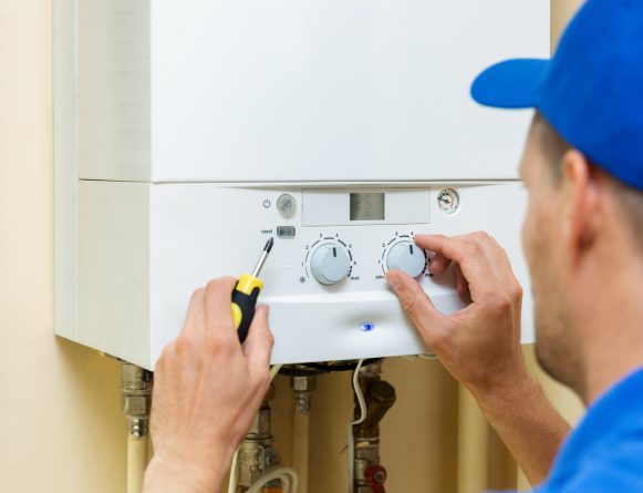 plumber in blue hat tests a combi boiler post installation